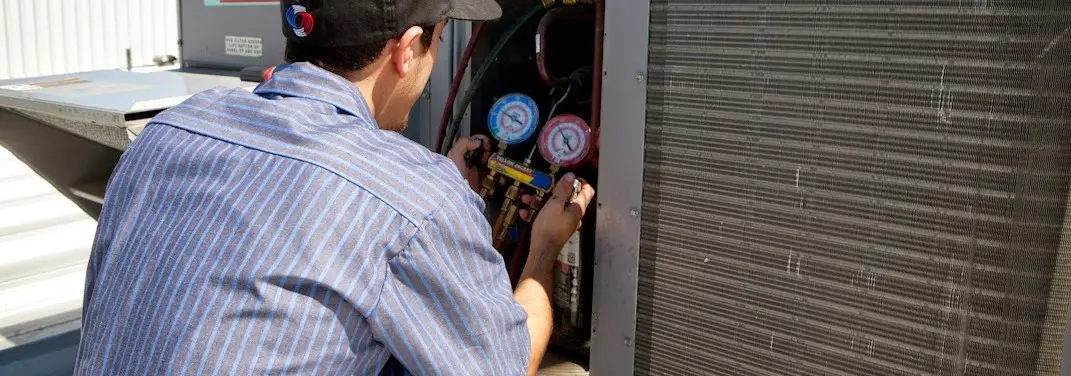 HVAC technician servicing a condenser unit in Edwardsville